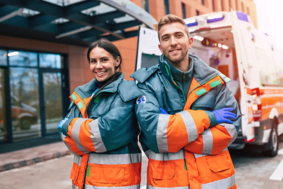 Emergency Medical Technicians Smiling Standing Besides Ambulance